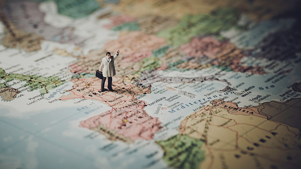 muñeco hombre, con maletin, parado sobre mapa de Europa