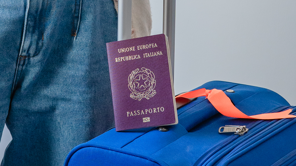 Pasaporte italiano apoyado sobre una valija